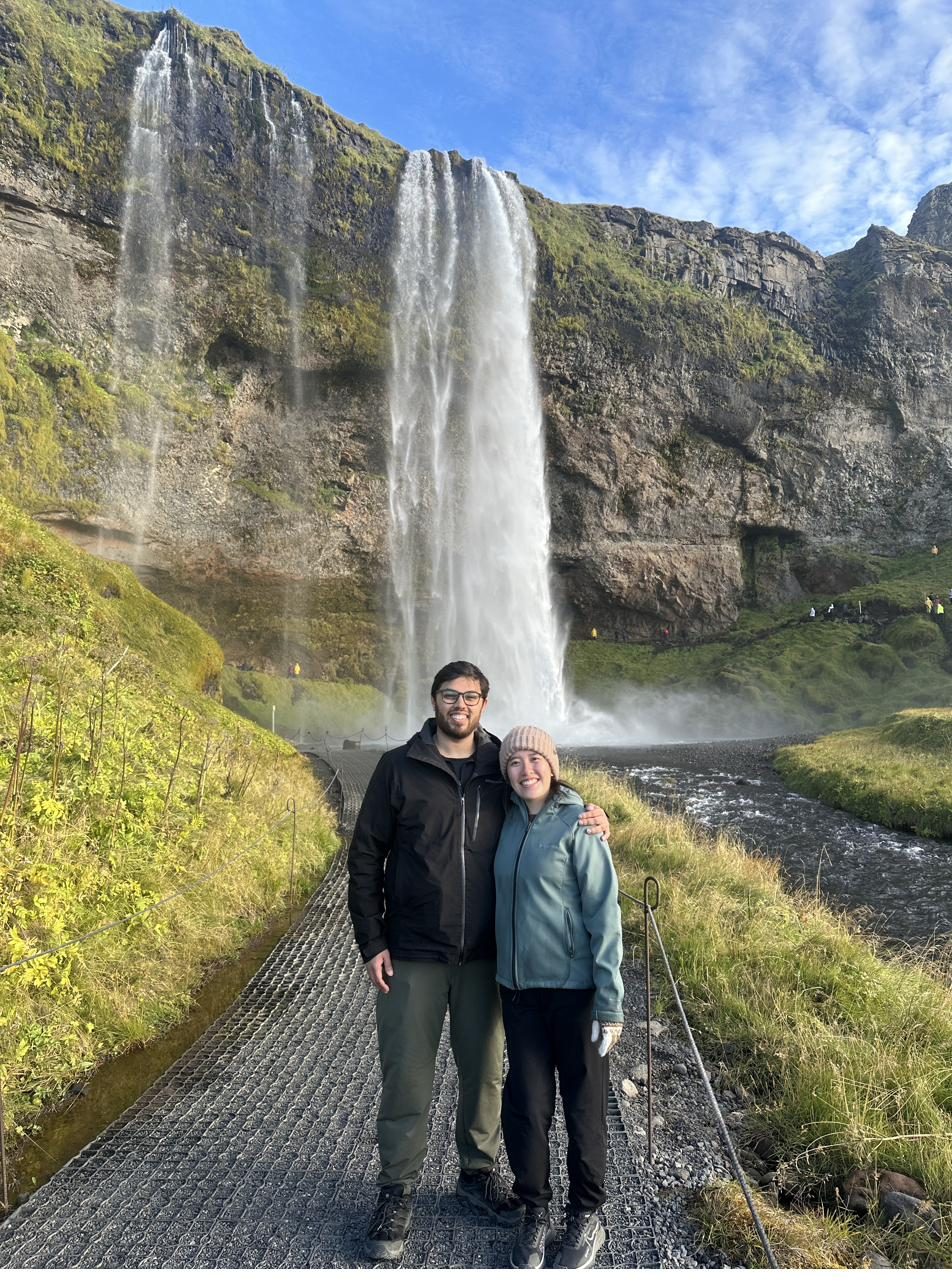 Jocelyn and Devanshu in front of Seljalandsfoss waterfall in Iceland